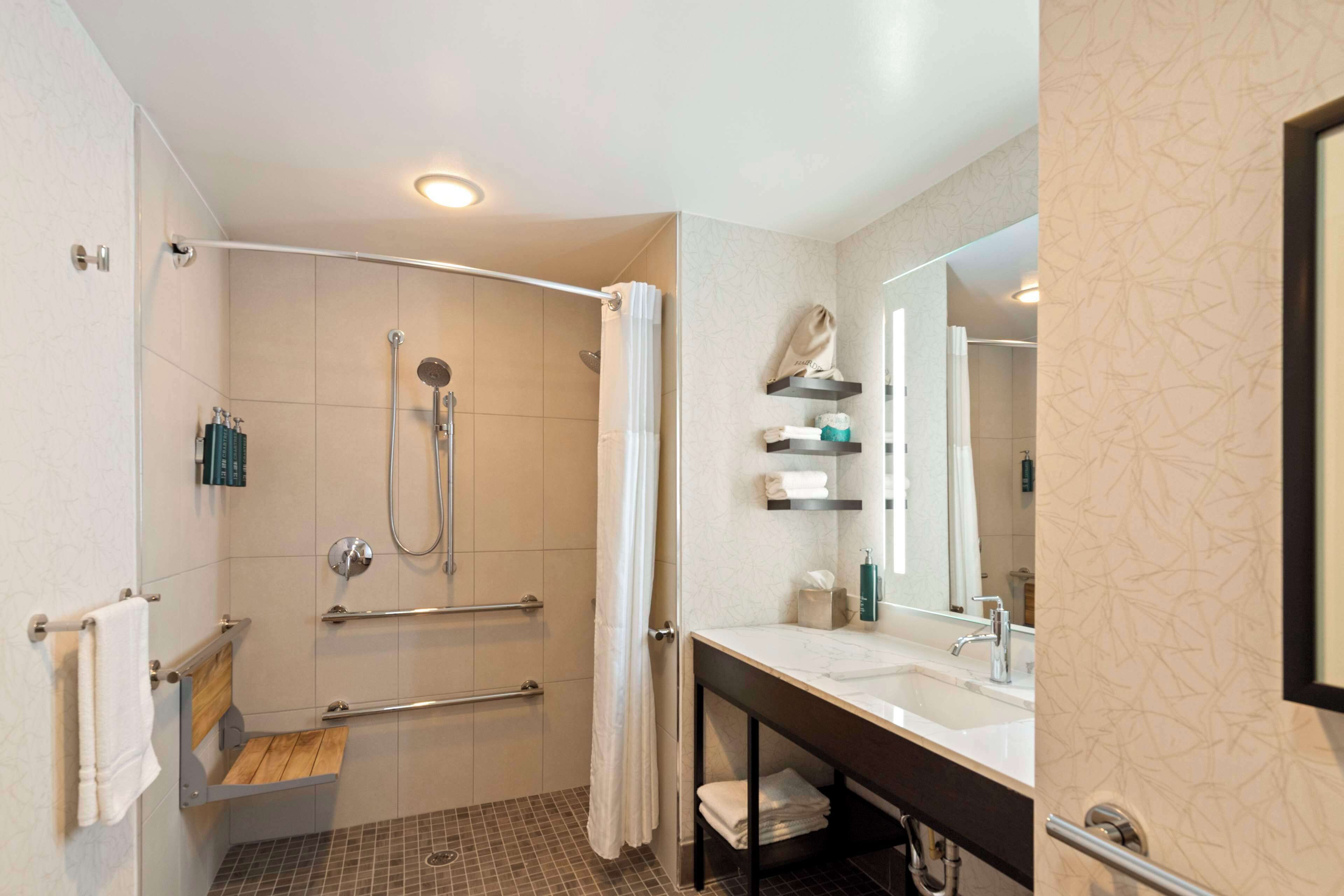 Une salle de bain moderne équipée d’une douche, d’un lavabo et d’un miroir.