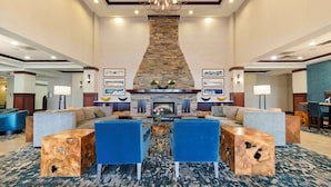 A spacious lobby with a stone fireplace, blue upholstered sofas, and a chandelier. - DoubleTree by Hilton Front Royal Blue Ridge Shadows (Front Royal)