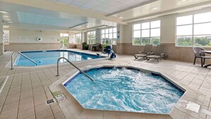 An indoor swimming pool with a hot tub, lounge chairs, and a view of the outdoors. - DoubleTree by Hilton Front Royal Blue Ridge Shadows (Front Royal)