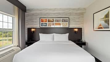 A hotel room with a large bed, a view of a lake, and a framed artwork above the bed.