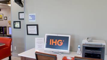 A business center with a computer, printer, and a sign indicating it's open 24 hours.