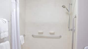 A shower with a glass door, a grab bar, and a handheld showerhead.