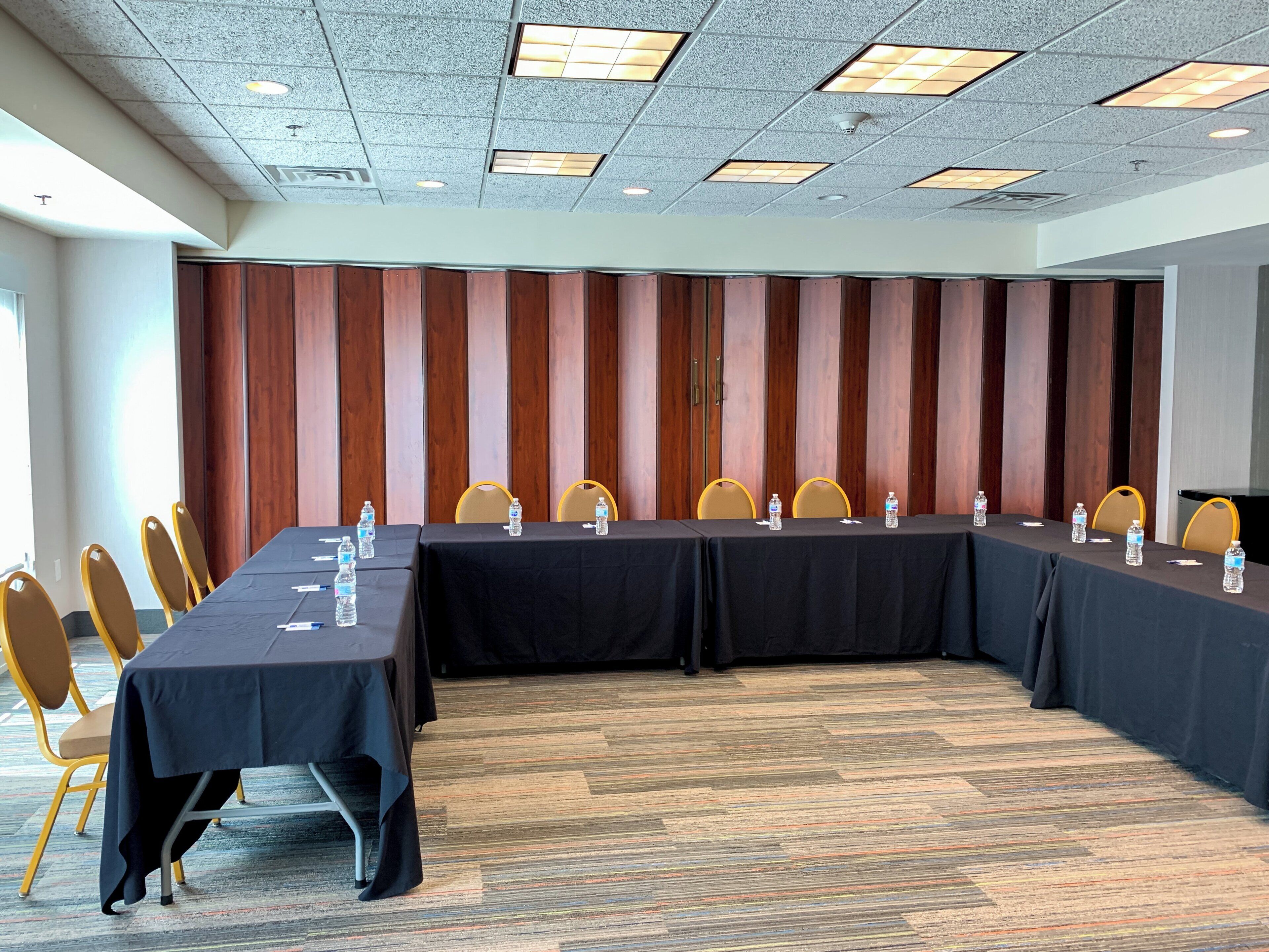 Un salón de conferencias con una larga mesa, sillas y botellas de agua.