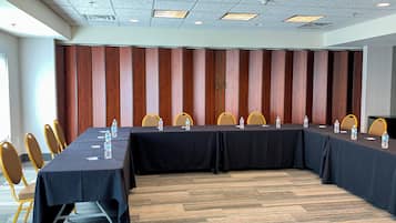 Un salón de conferencias con una larga mesa, sillas y botellas de agua.