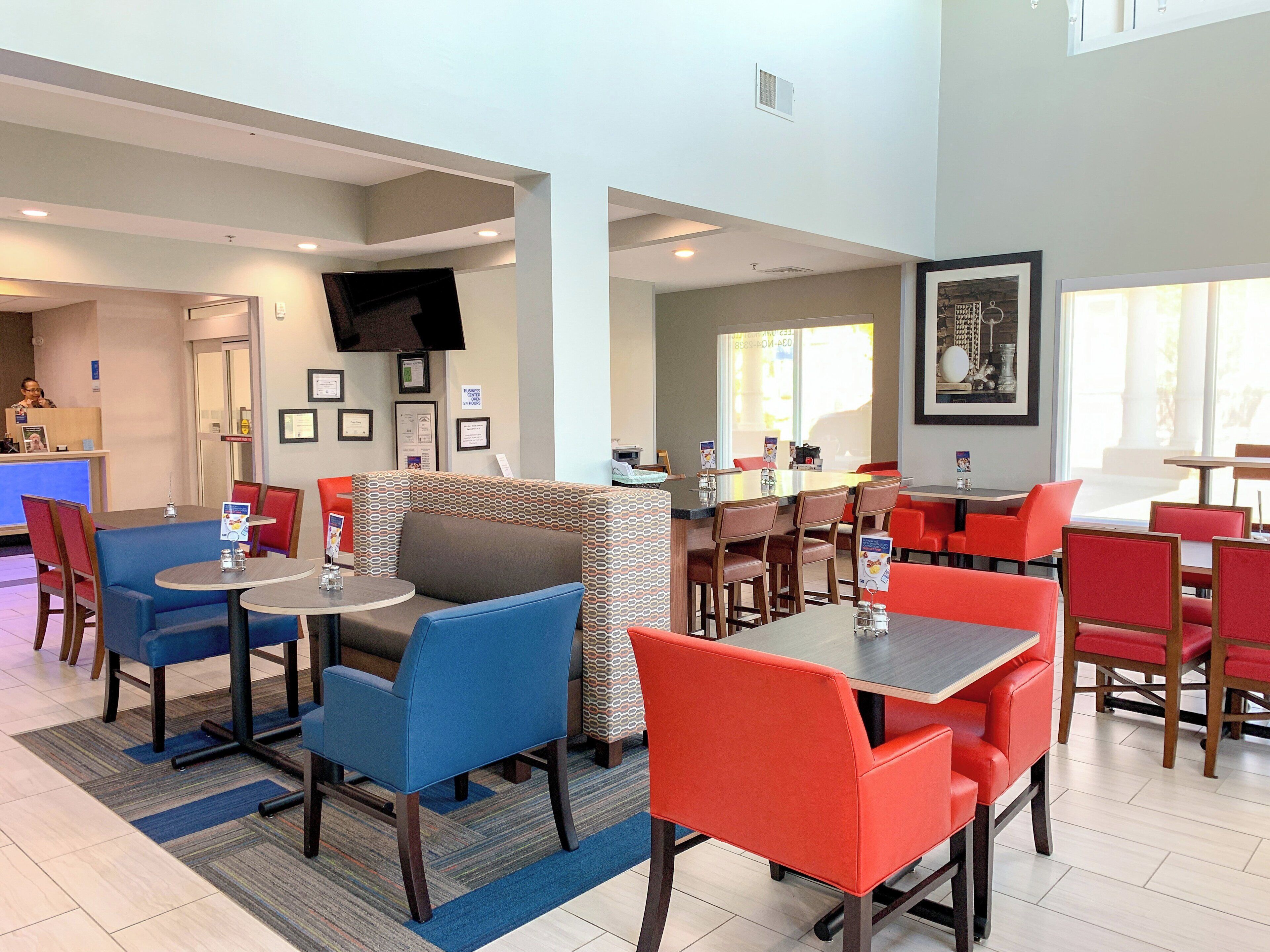 A hotel lobby with seating areas, a reception desk, and a television.