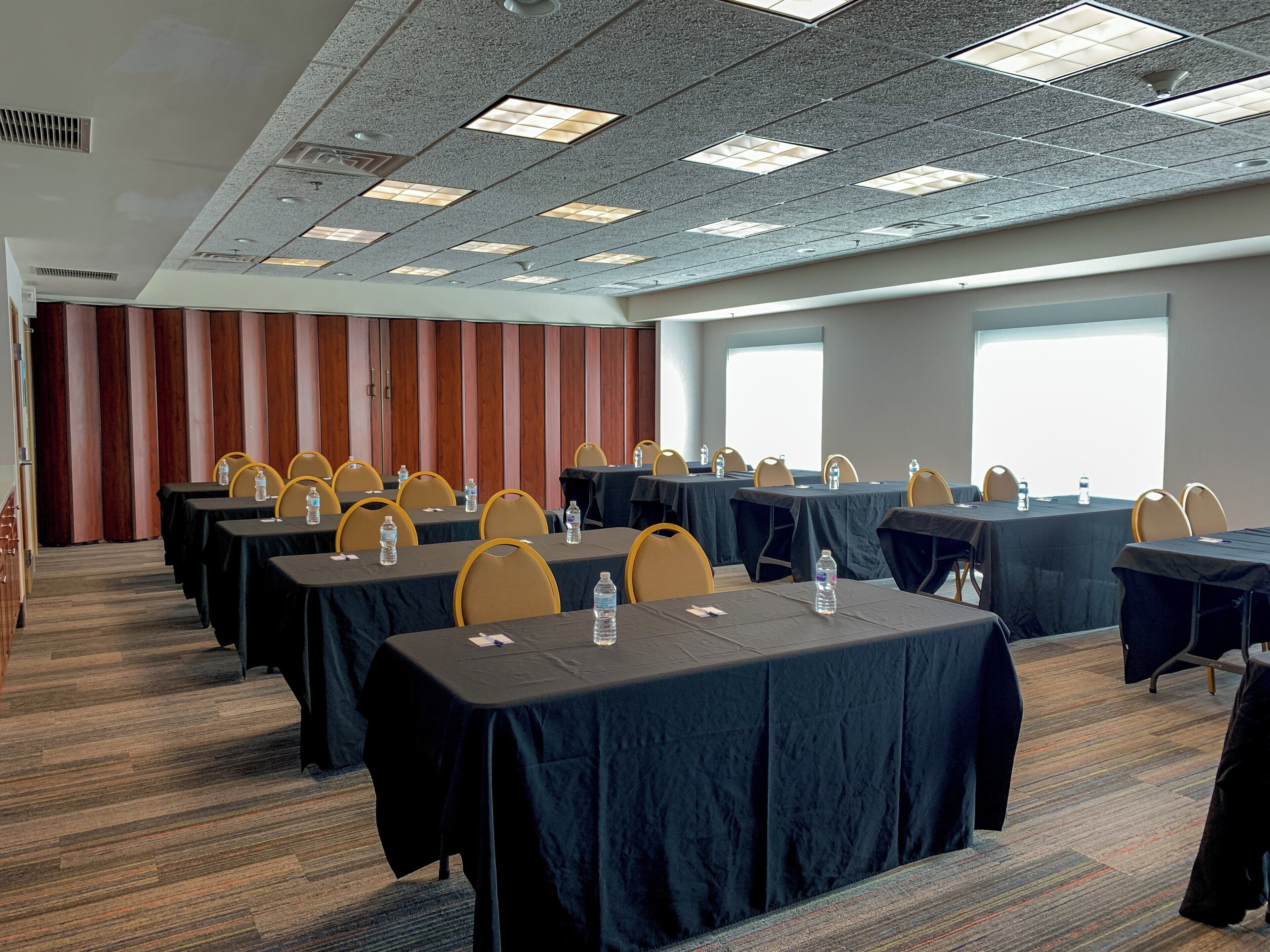A conference room with multiple tables, chairs, and water bottles.
