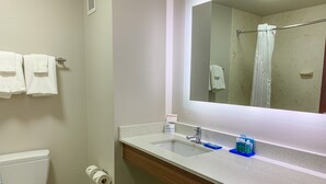 A bathroom with a white toilet, a sink with a mirror above it, and a towel rack with two towels.