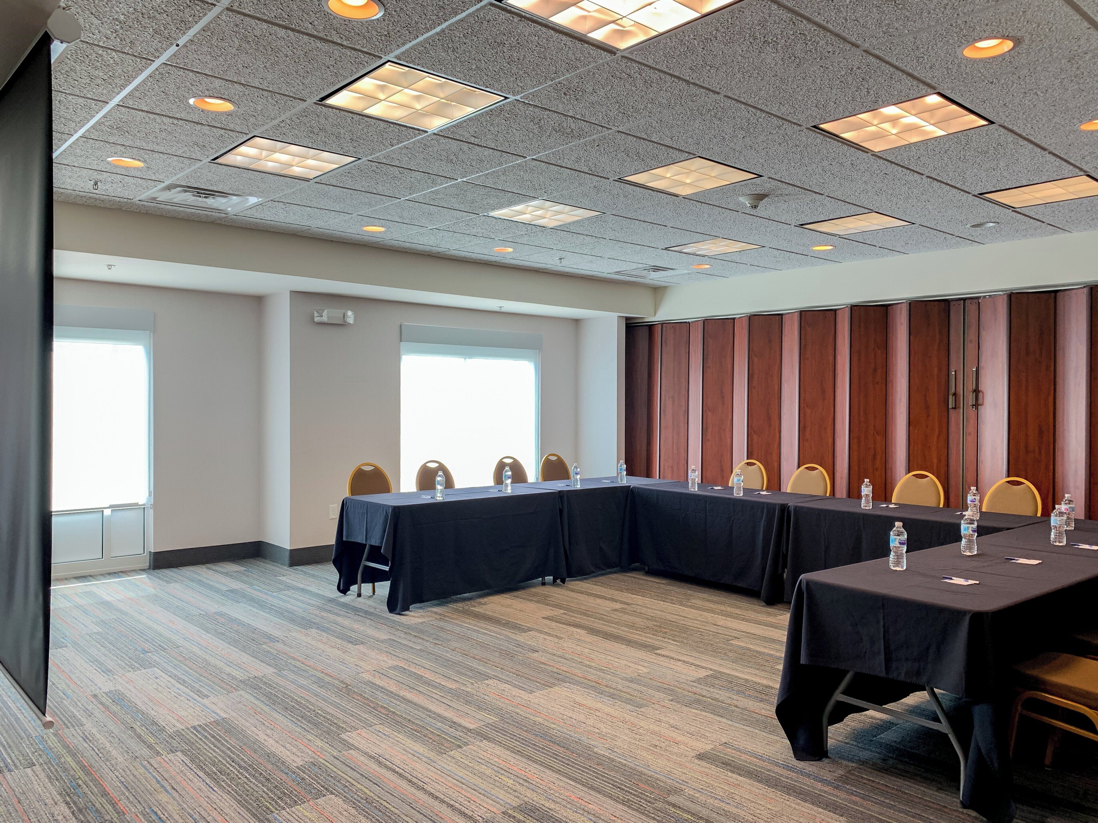 A conference room with a long table, chairs, and a carpeted floor.