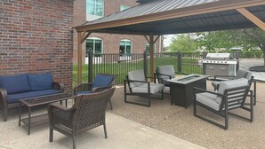 An outdoor patio with wicker furniture, a grill, and a covered area.