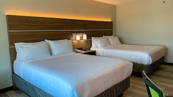 Habitación de hotel con dos camas, cabecera de madera, mesita de noche con teléfono y lámpara de pared.