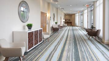Een hotellobby met een lange gang, zithoeken en een receptiebalie.