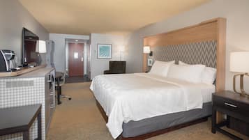A hotel room with a bed, desk, chair, and a television.
