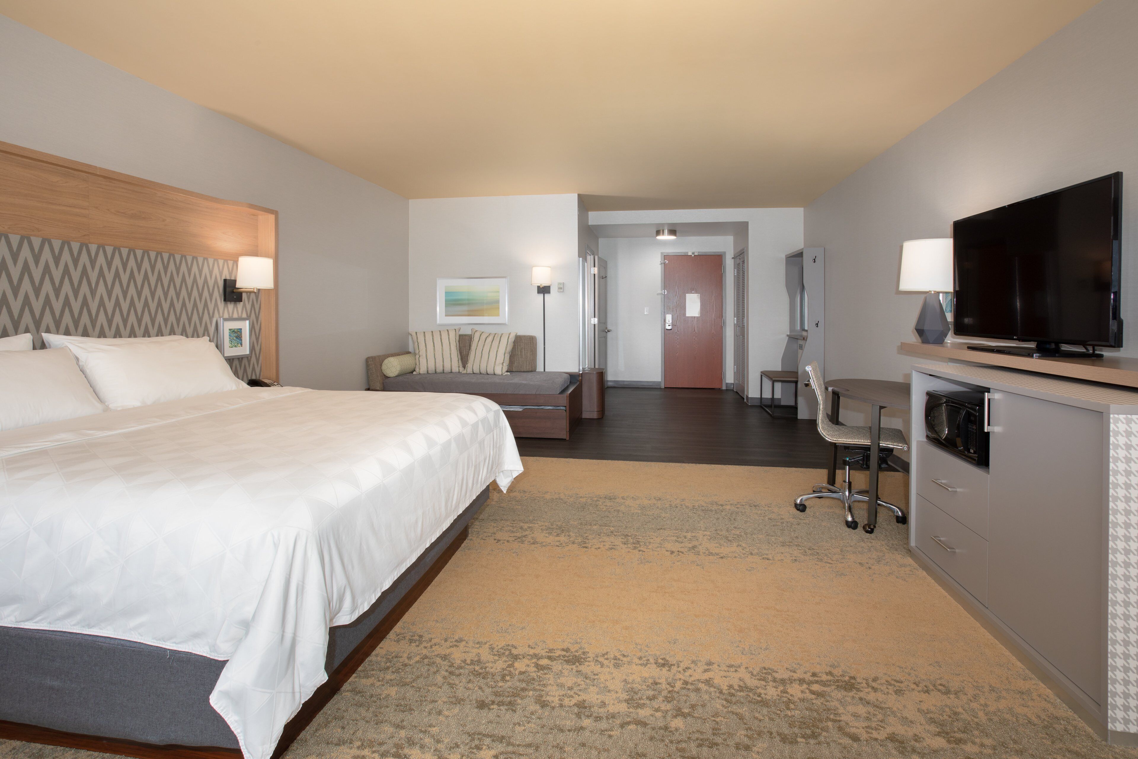 Een hotelkamer met een groot bed, een bureau, een televisie en een zithoek.
