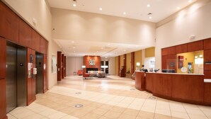 A spacious lobby with a checkered floor, a reception desk, and a seating area with a sofa and chairs. - Holiday Inn Winchester Se-Historic Gateway by IHG (Winchester)