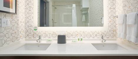 Une salle de bain avec deux lavabos, un grand miroir et une douche.