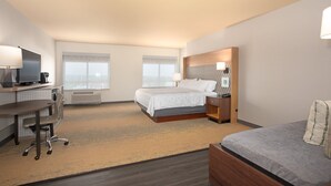 A hotel room with a bed, a desk with a computer, a chair, and a TV. - Holiday Inn Winchester Se-Historic Gateway by IHG (Winchester)