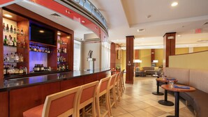A bar area with a counter, multiple bar stools, and a television screen. - Holiday Inn Winchester Se-Historic Gateway by IHG (Winchester)