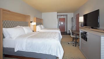 A hotel room with two beds, a desk, a television, and a microwave.