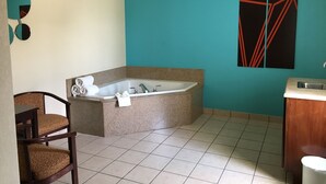 Un baño con una bañera independiente, un lavamanos y una silla.