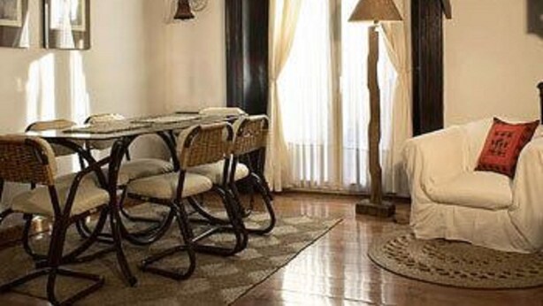 Un coin repas comprenant une table et des chaises, une lampe et un canapé avec un coussin.