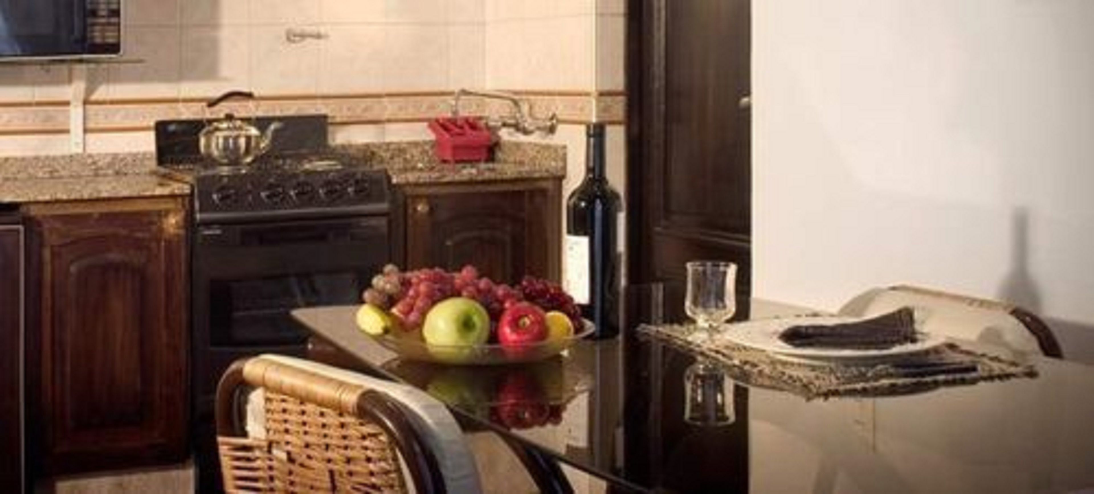 A kitchen with a stove, a sink, and a fruit bowl on the counter.
