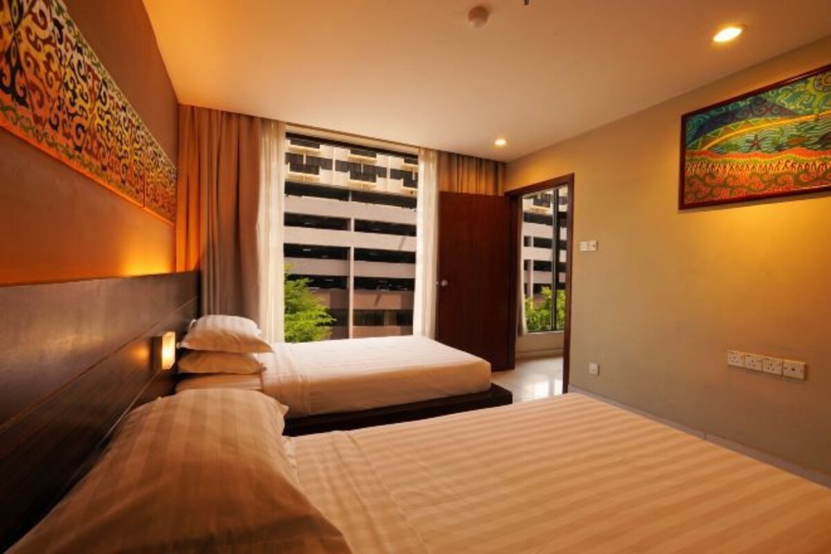 Ein Hotelzimmer mit zwei Betten, einem großen Fenster mit Jalousien, einem Bild an der Wand und einer Tür, die nach draußen führt.