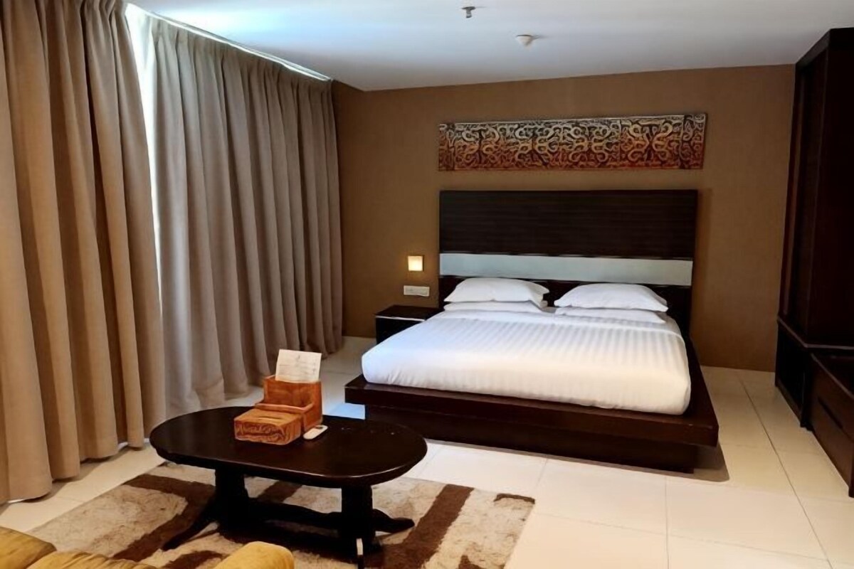 A hotel room with a bed, bedside table, and a nightstand.