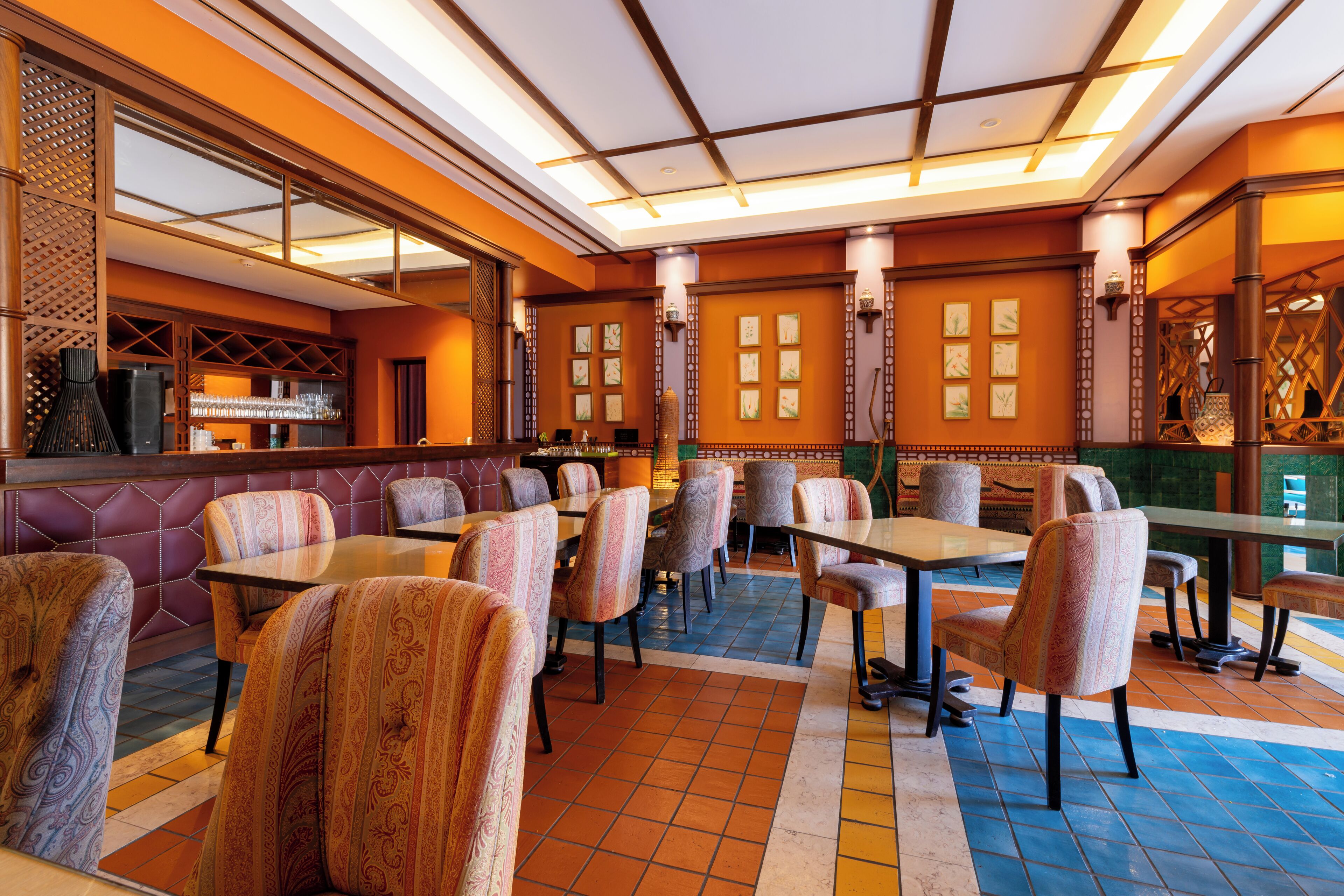 Ein Restaurant mit hoher Decke, gemusterten Stühlen und einem gefliesten Boden.