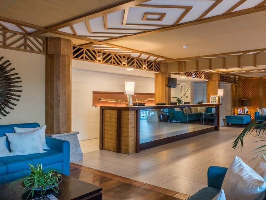 Un hall d’hôtel avec un canapé bleu, un comptoir d’accueil et un grand miroir au mur.