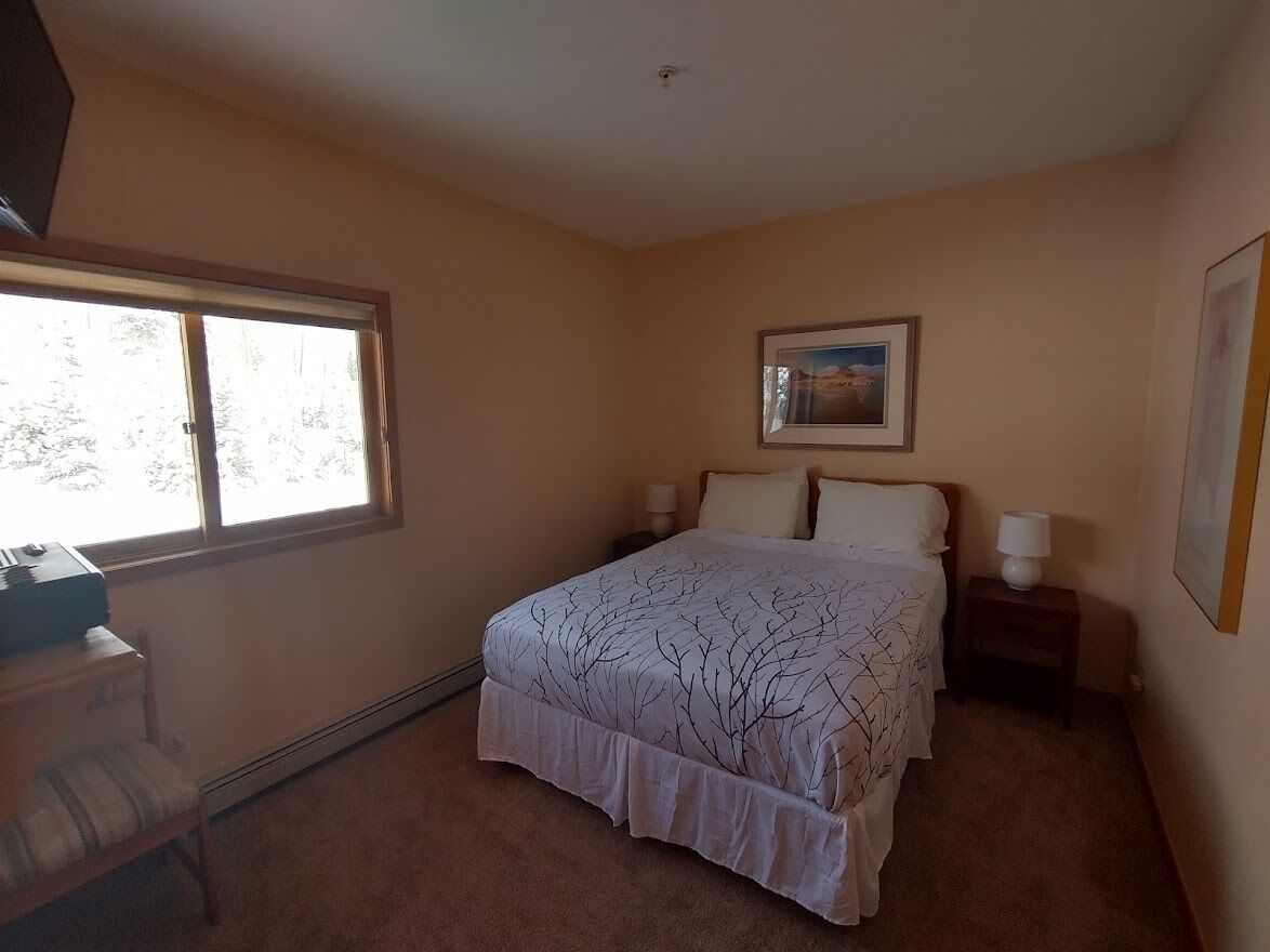 A bedroom with a bed, a desk, a chair, a window, and a picture on the wall.