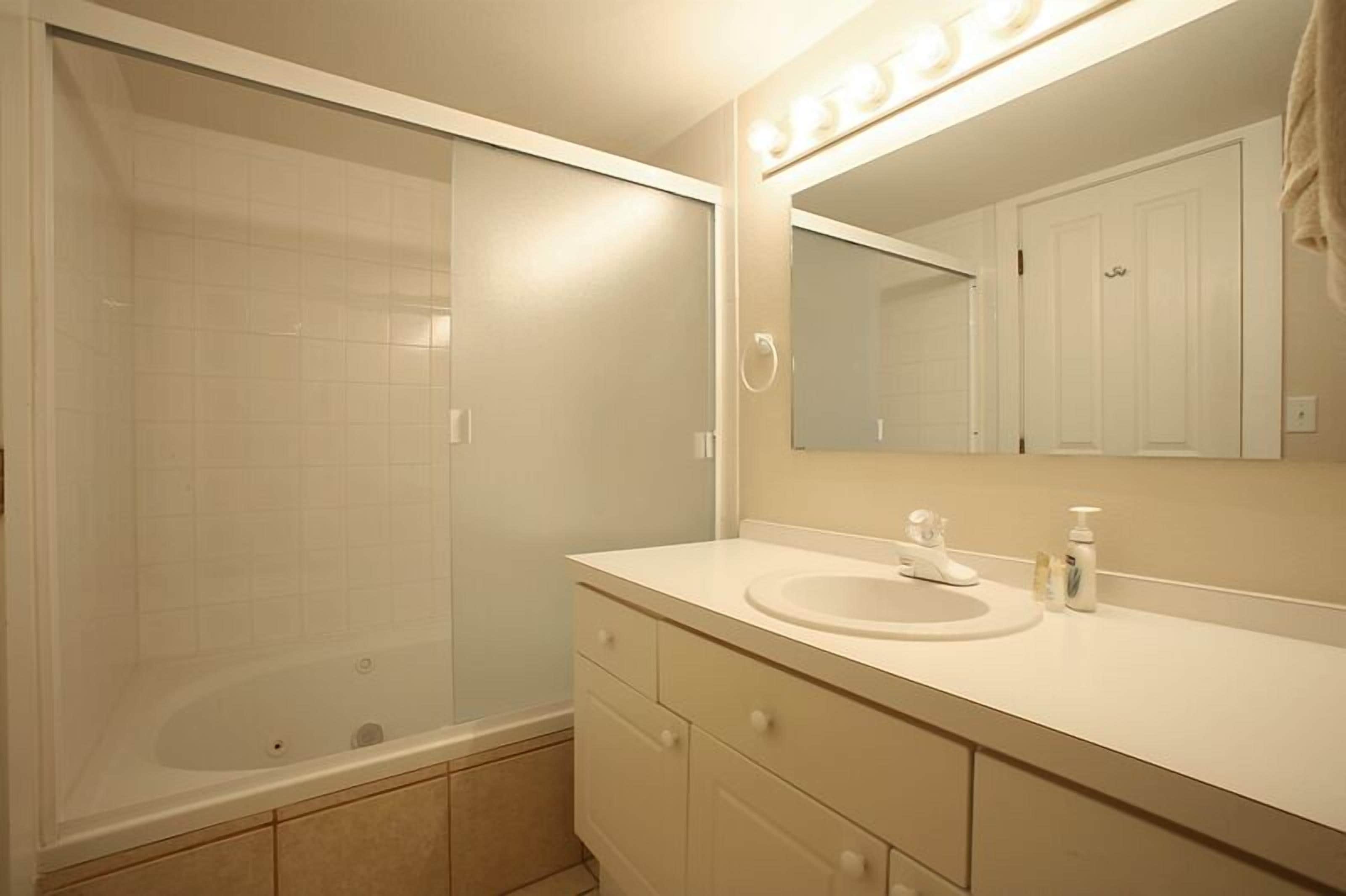A bathroom with a bathtub, a sink, and a mirror.