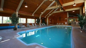 Ein Hallenbad mit Holzbalken, Liegestühlen und Topfpflanzen.