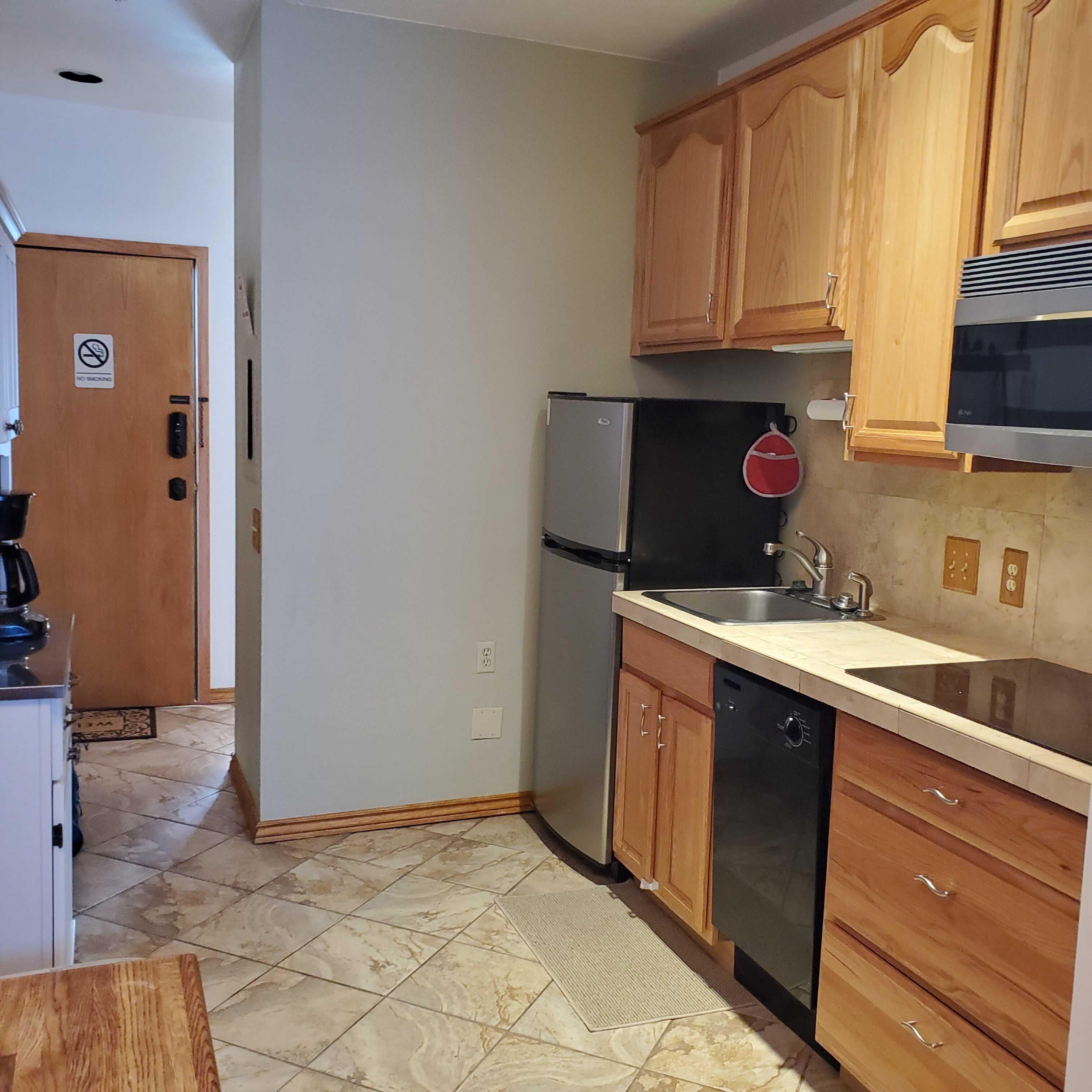 A kitchen with wooden cabinets, a stainless steel refrigerator, a dishwasher, and a microwave.