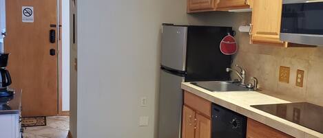 A kitchen with wooden cabinets, a stainless steel refrigerator, a dishwasher, and a microwave.