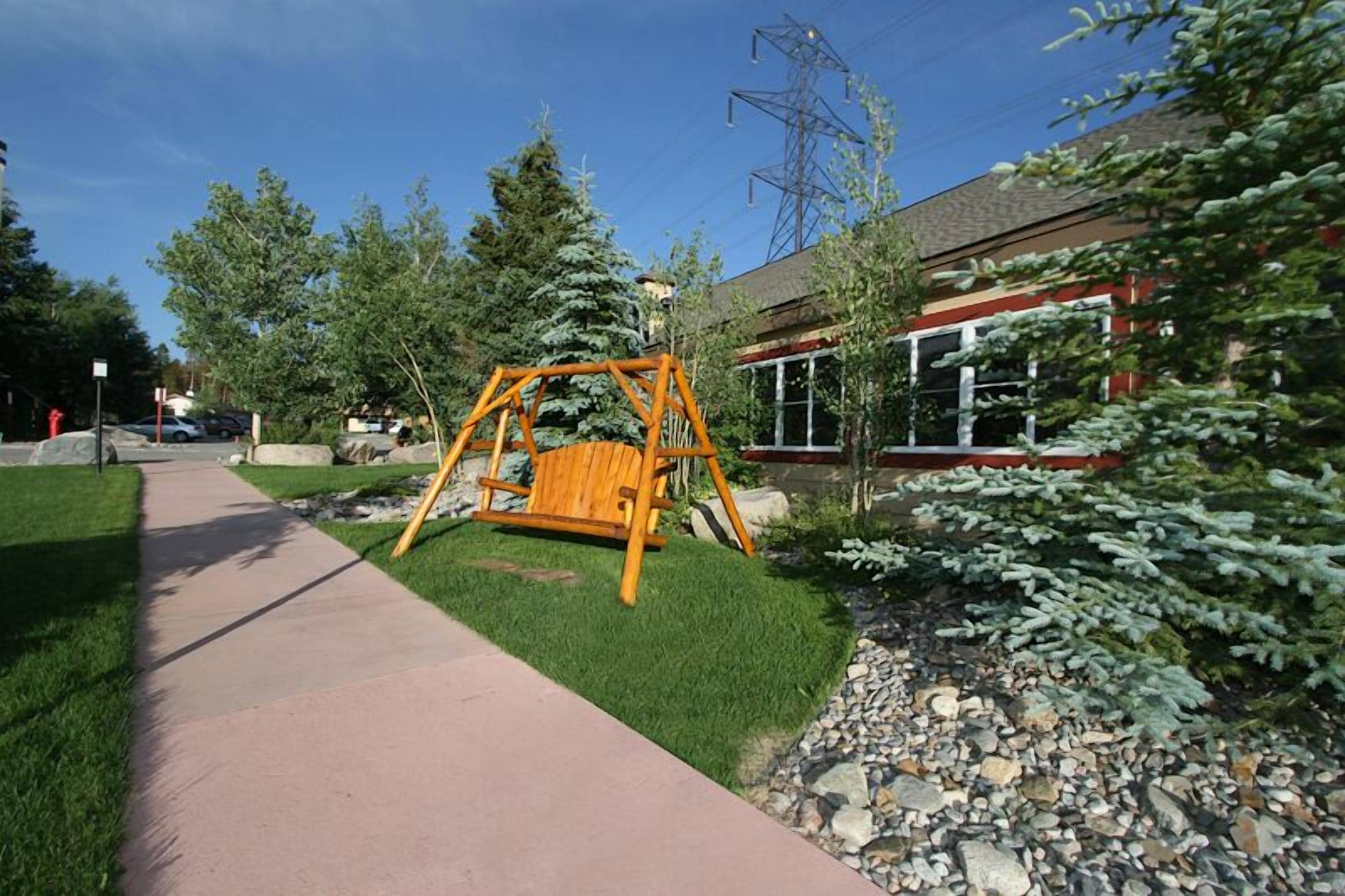 A swing set in a park area with a building in the background.