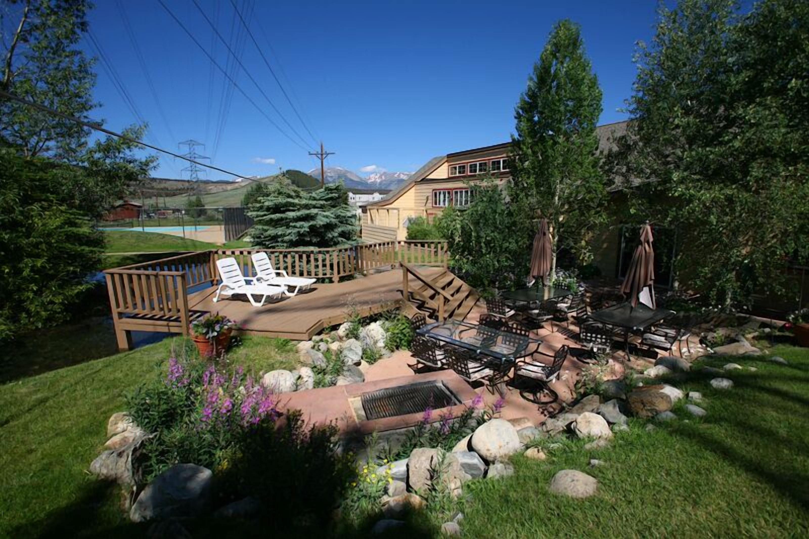 A backyard with a wooden deck, outdoor furniture, and a grill area.