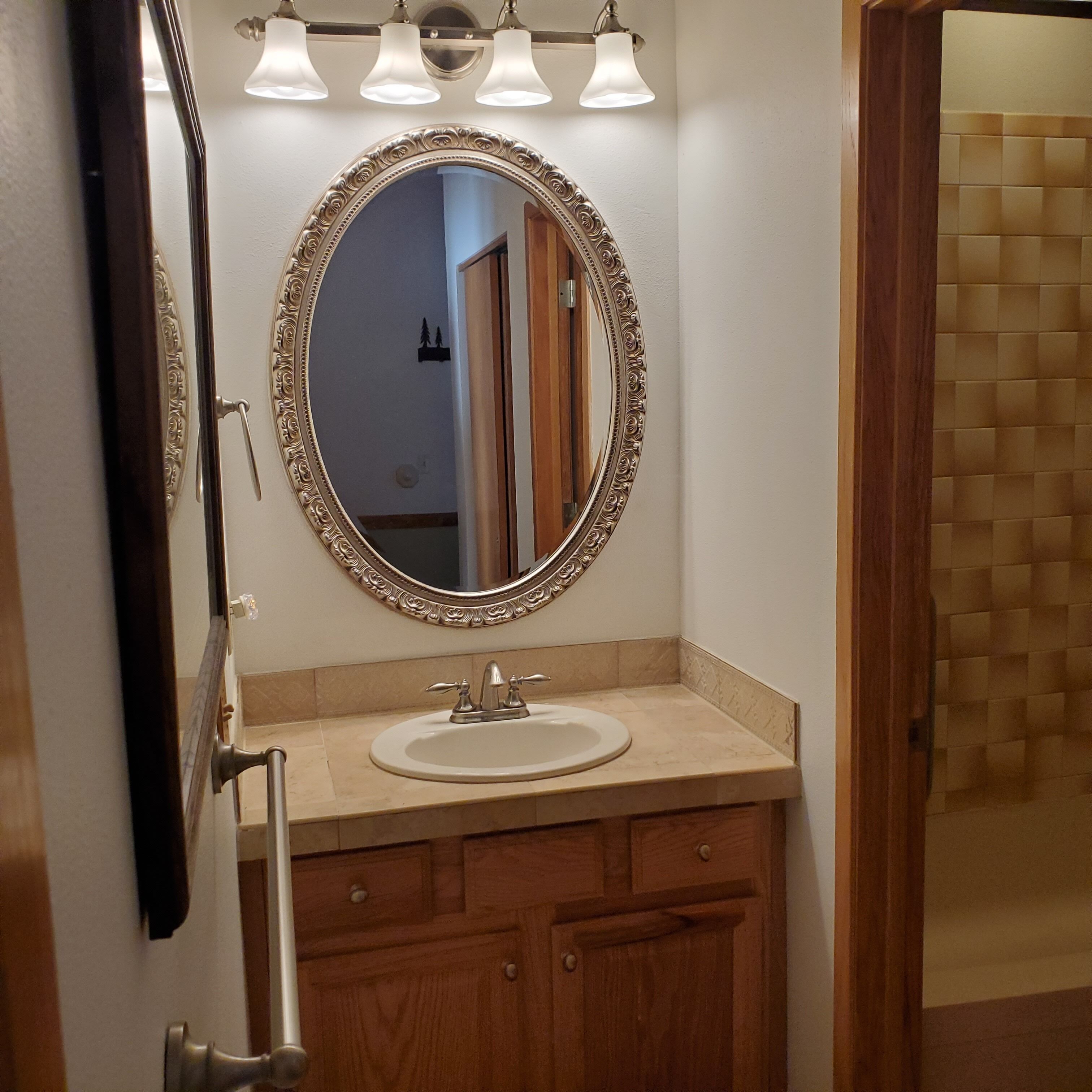 A bathroom with a round mirror, a sink, and a wooden vanity.