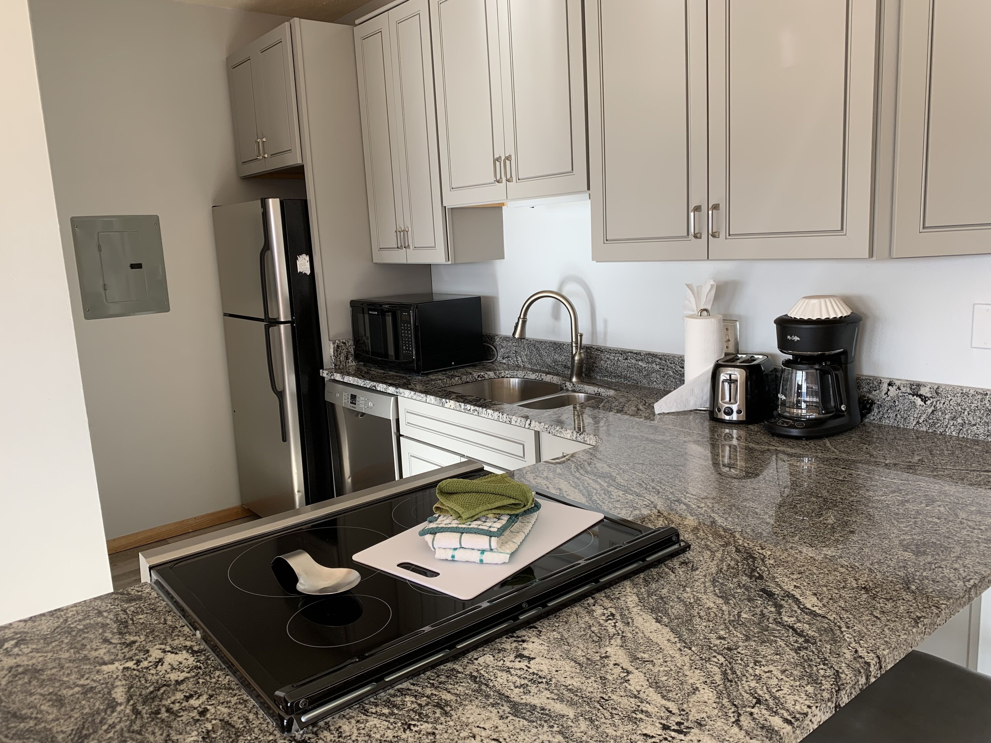 A modern kitchen with granite countertops, stainless steel appliances, and white cabinetry.