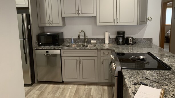 A compact kitchen with grey cabinets, a microwave, a coffee maker, and a dishwasher. - Swan Mountain Resort (Dillon)