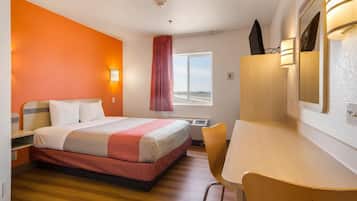 Une chambre d’hôtel avec un lit, un bureau, une chaise et une fenêtre donnant sur un paysage agréable.