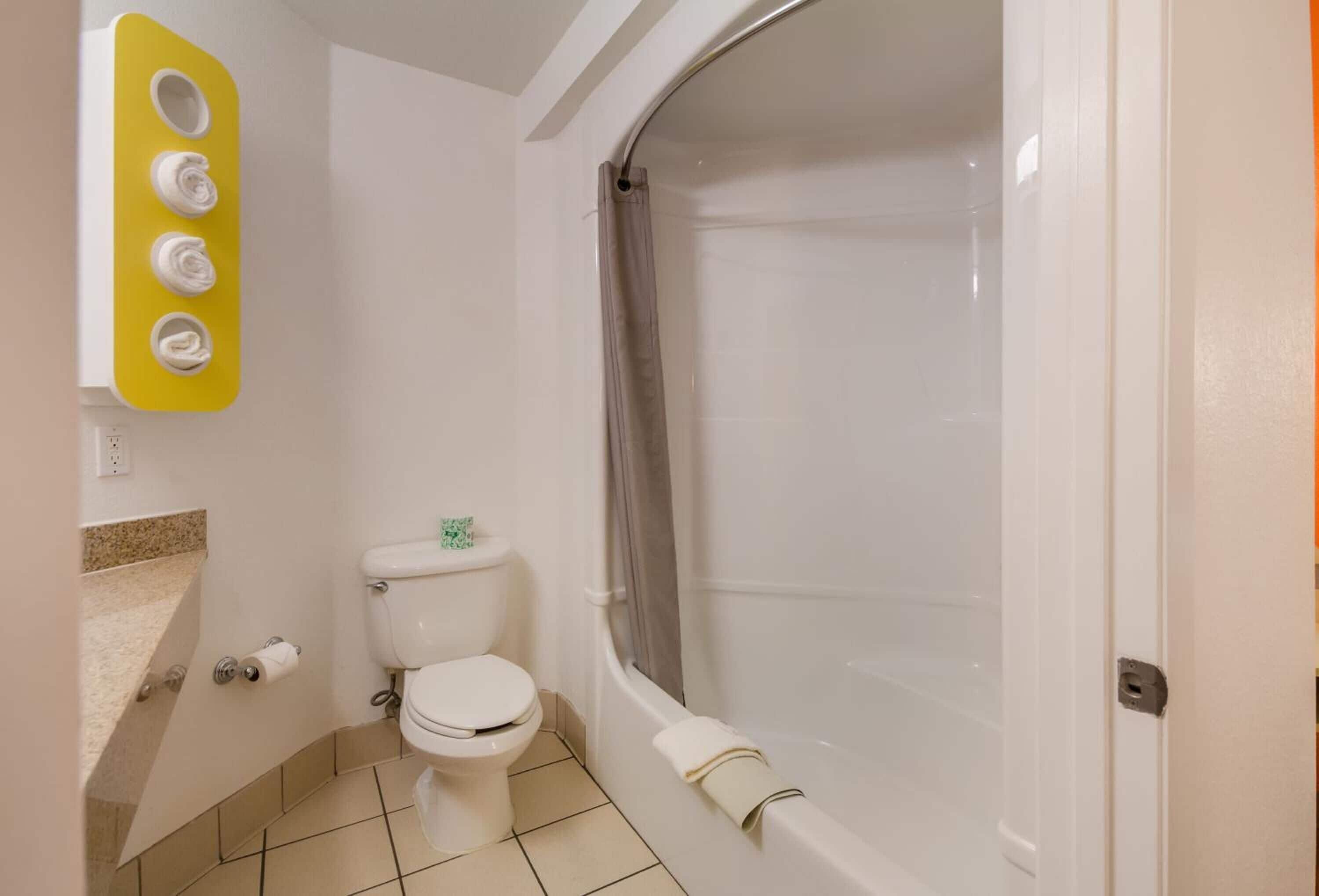 Un baño con inodoro, bañera y toallero amarillo.