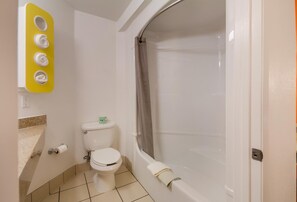 Une salle de bain équipée de toilettes, d’une baignoire et d’un porte-serviettes jaune.