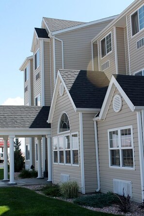 A two-story house with a covered porch, a dark roof, and beige siding. - Microtel Inn and Suites by Wyndham Rawlins (Rawlins)