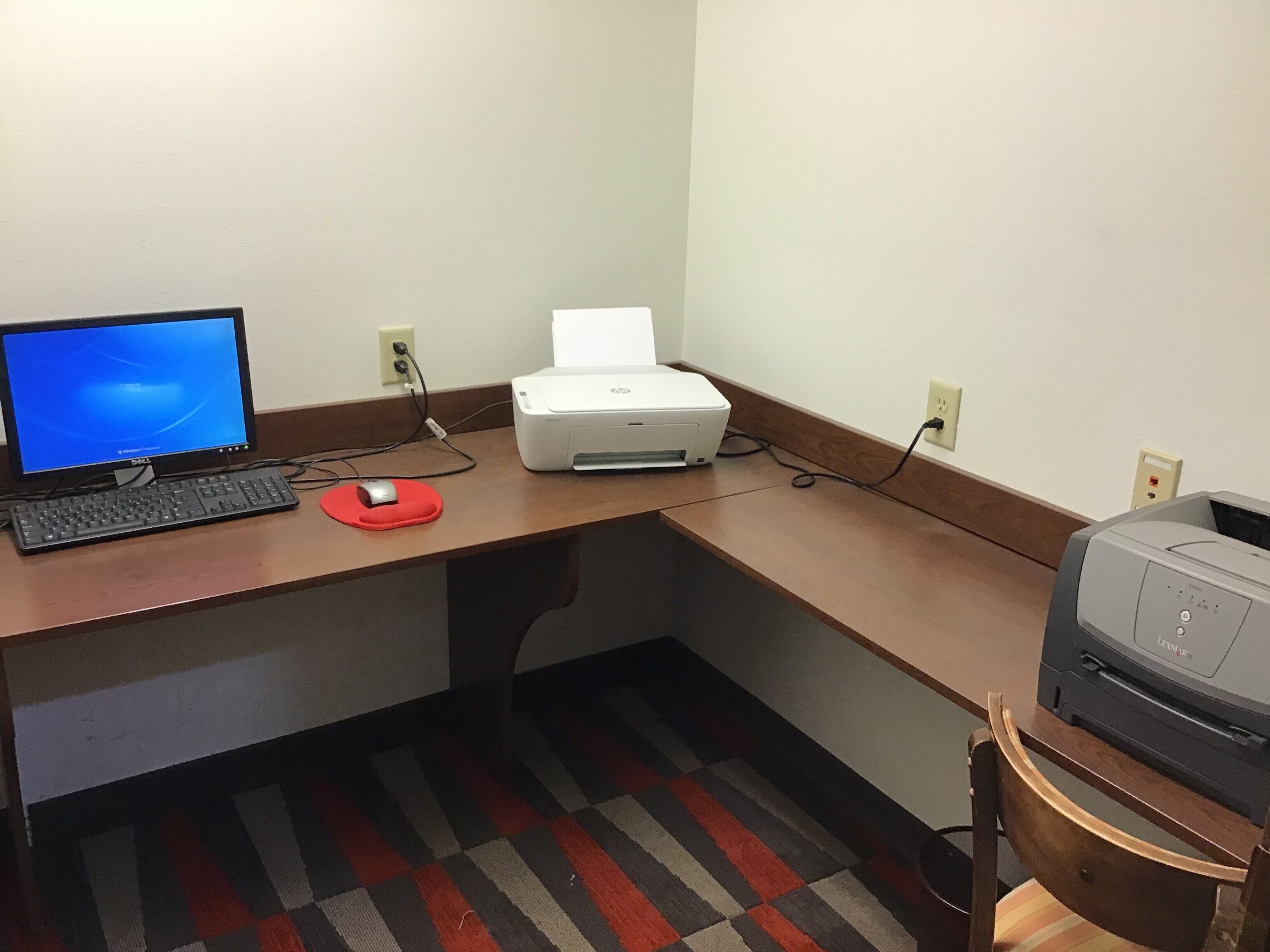 A desk with a computer, printer, and a chair.