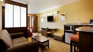 A compact hotel room with a kitchenette, a TV, and a bed.