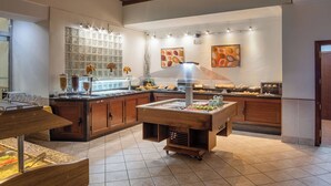 Una mesa de buffet con diversos alimentos y una pared decorativa con arte abstracto.