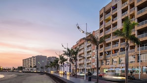 Un hotel con múltiples balcones, ubicación frente a la playa y cielo despejado.