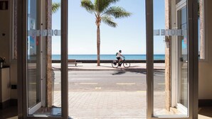 Vista a través de un vidrio de una calle con un ciclista y una palmera.