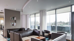 Un espace lounge moderne avec des sièges en cuir, de grandes fenêtres et une vue sur la ville.