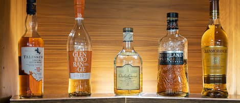 A wooden shelf with five bottles of whisky.